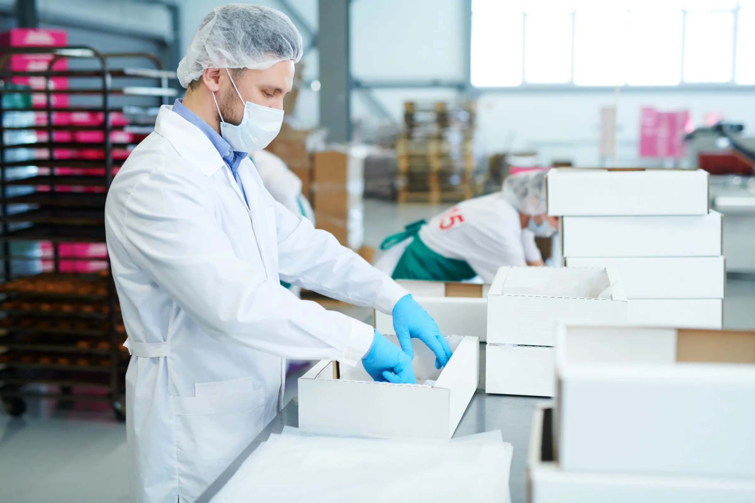 Operatore in camice e guanti prepara colli di materiale medicale in magazzino.