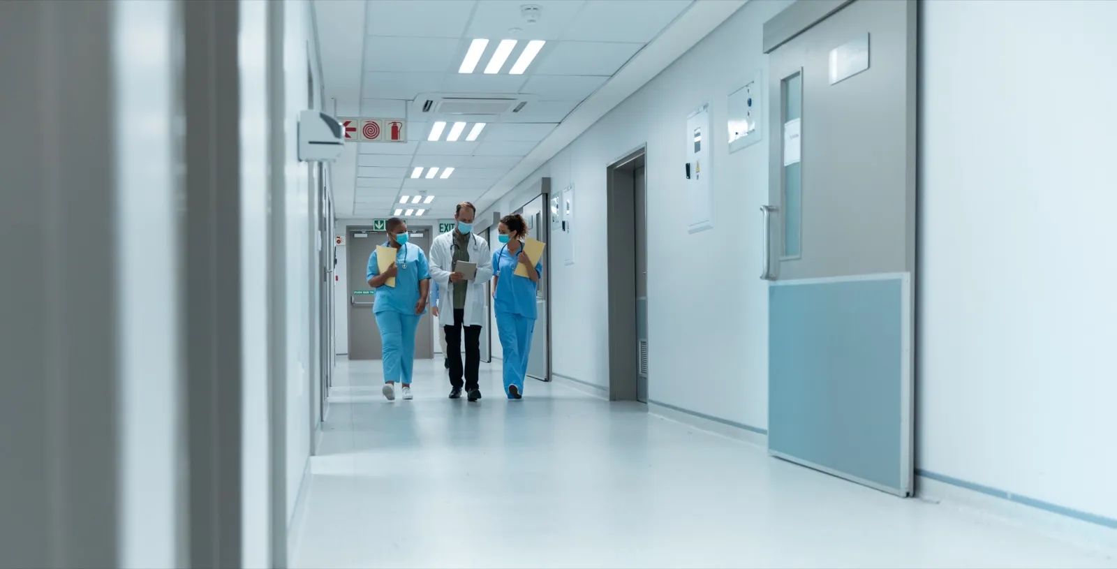 Corridoio di reparto con personale sanitario sullo sfondo.